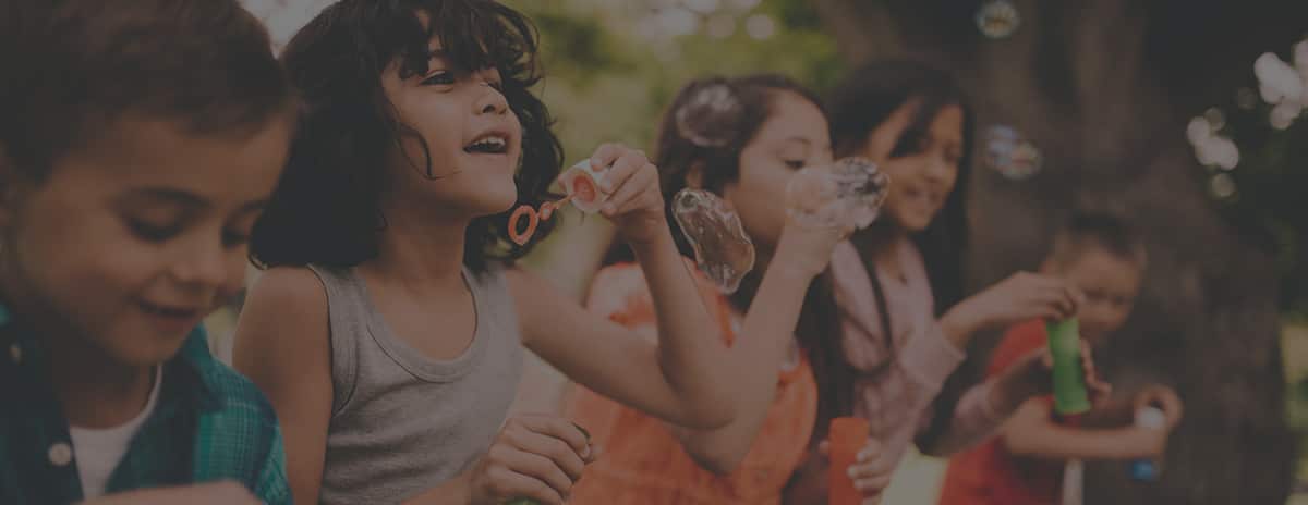 Children blowing soap bubbles together outdoors on a summer day