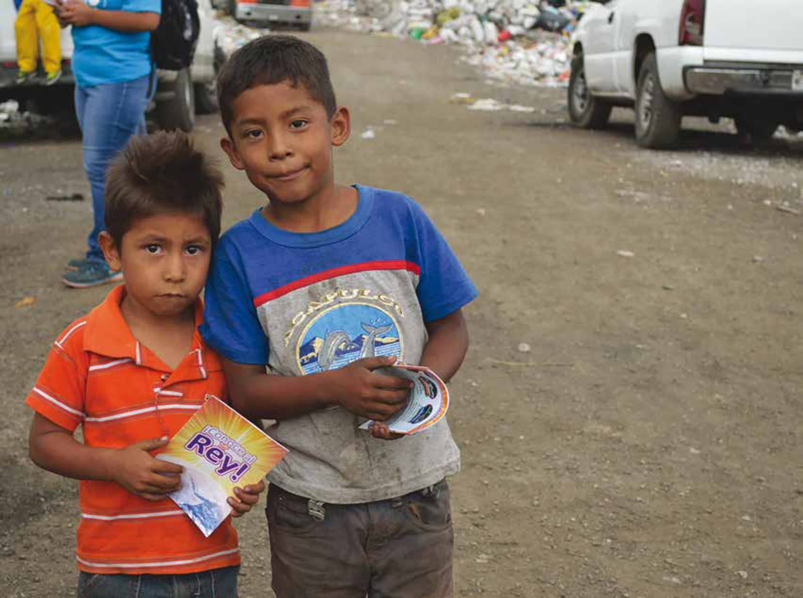 Two young boys in Mexico City holding Gospel tracts and smiling at the camera