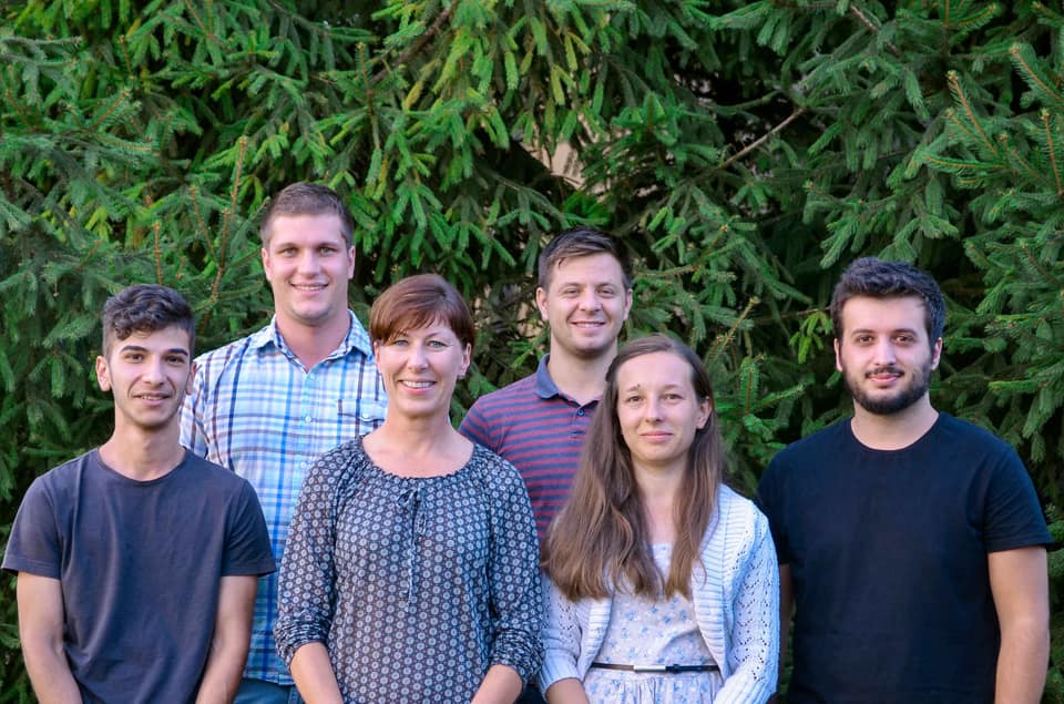 Six CEF training students and staff standing together in front of evergreen trees